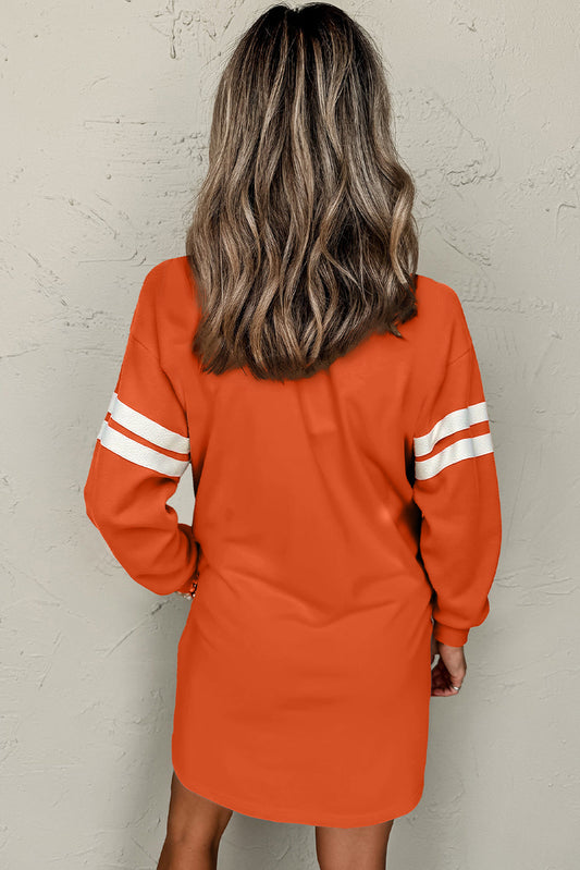 Person wearing an orange dress with white stripes on a plain background